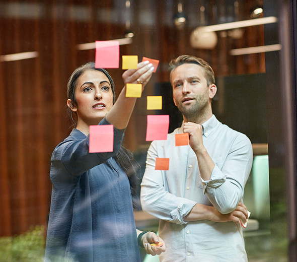 To mennesker står og sætter post-its på et vindue