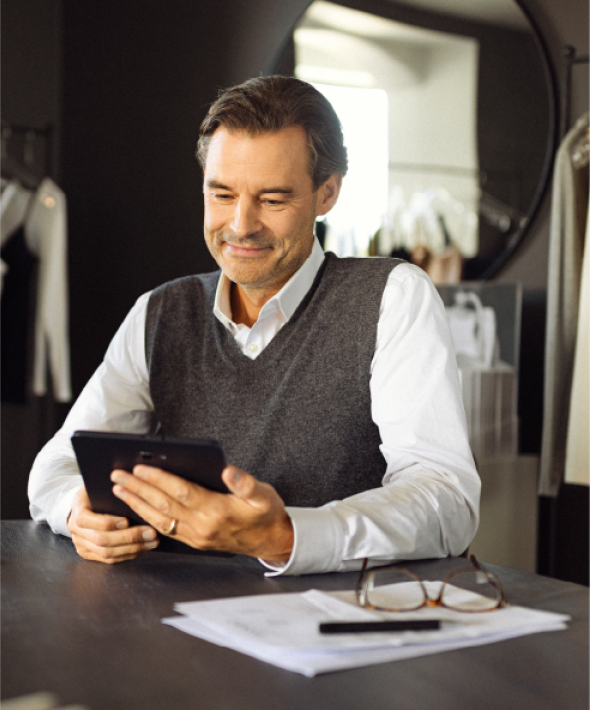 En mand sidder og kigger på sin tablet ved et bord i en butik