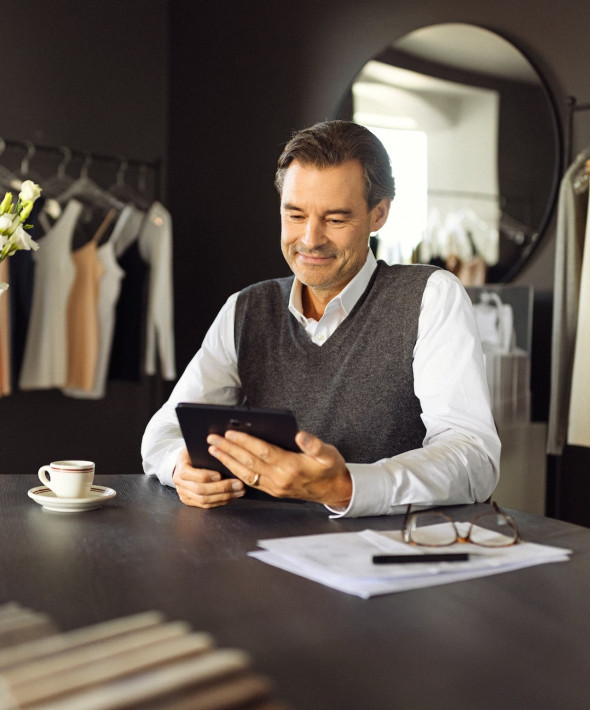 En mand sidder i en butik og kigger på sin ipad